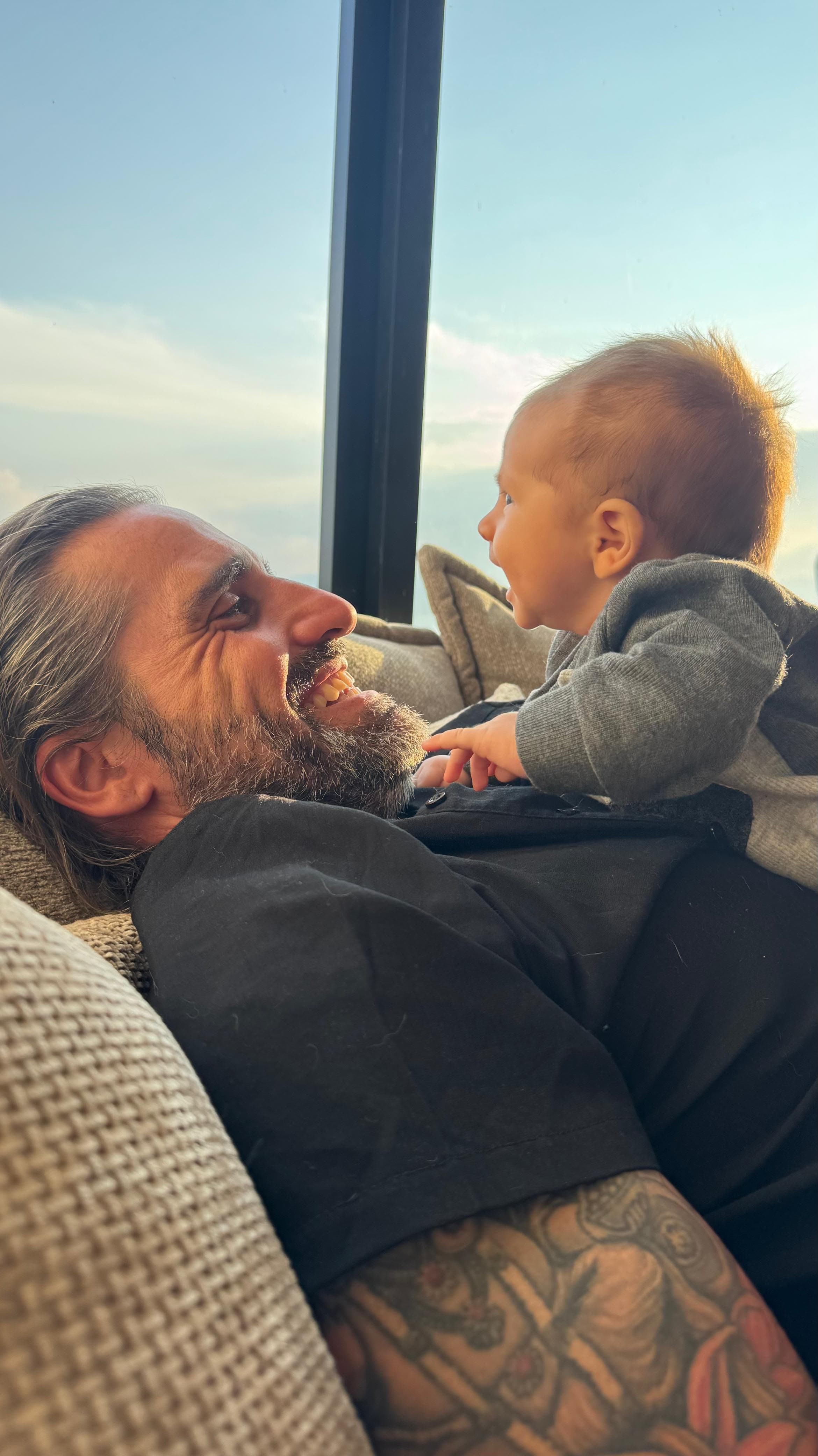 The builder laughing with his baby son at home above Lake Chapala, the lake and mountains through the window